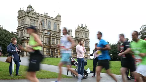 A group of runners running past a historical building as part of the Robin Hood half marathon
